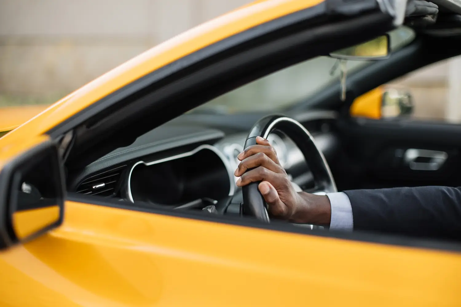 About Us Driver's hands on the steering wheel of a car at dusk