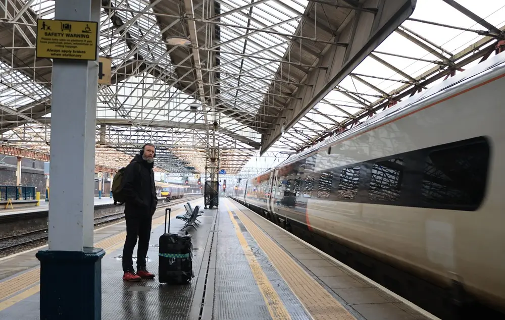 Areas Traveller with a suitcase waiting as a train arrives at a station